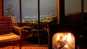 A cozy outdoor seating area with a wood-burning stove, a bench, and a potted plant. - Ayliya Bungalow (Akçaabat)