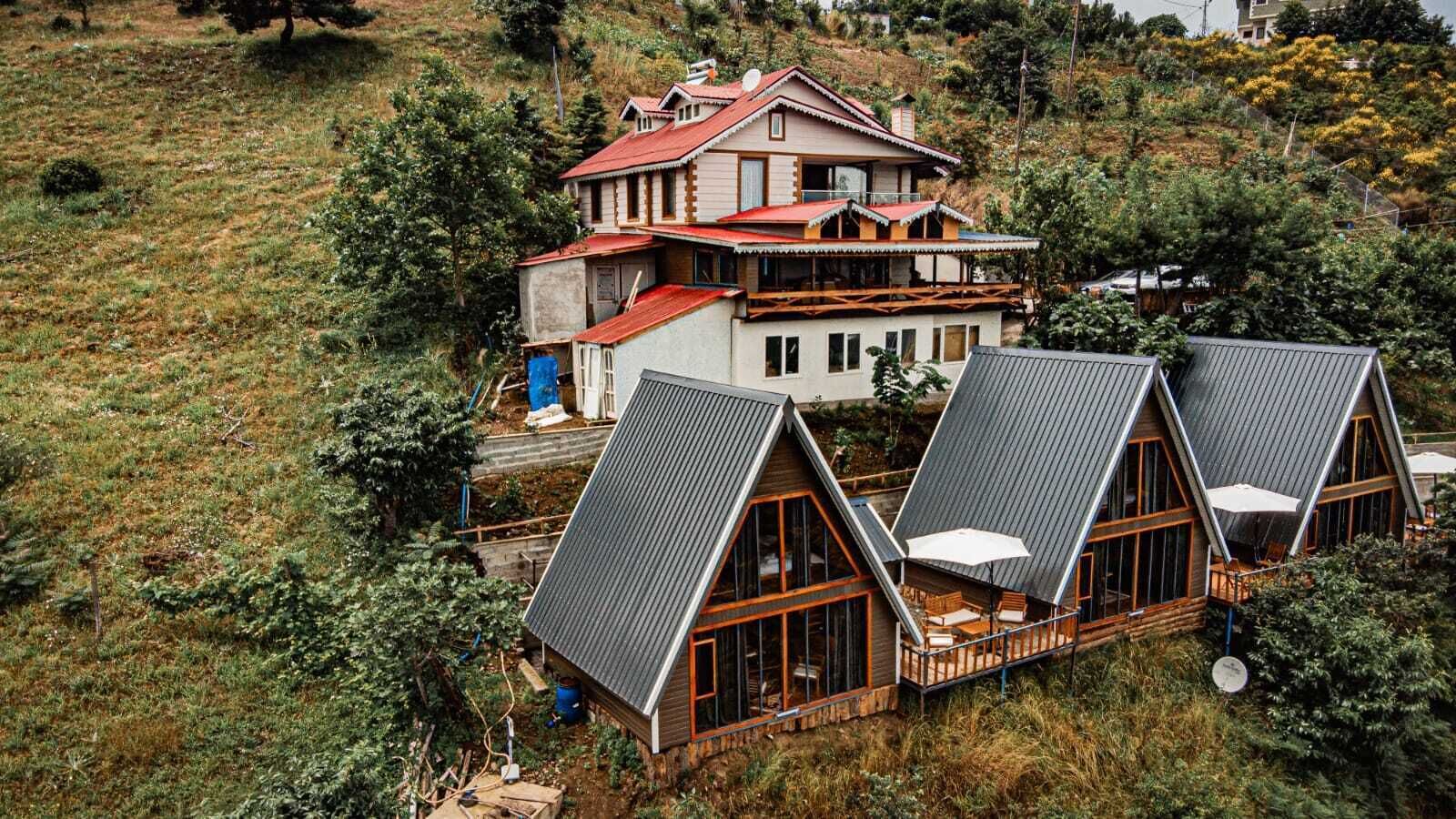 A house with a large balcony and a separate wooden structure with a sloped roof.