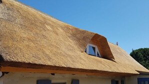 Ein Gebäude mit einem strohgedeckten Dach, einem kleinen Fenster und einer Tür mit einem Stern-Symbol.