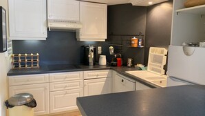 Eine kleine Küche mit weißen Schränken, einer schwarzen Arbeitsplatte, einer Kaffeemaschine, einem Wasserkocher und einem Toaster.