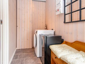 A laundry room with a washing machine, a dryer, a sink, and a bed with a patterned mattress.