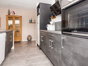 Ett modernt kök med grå skåp, en inbyggd ugn och en kaffebryggare.
