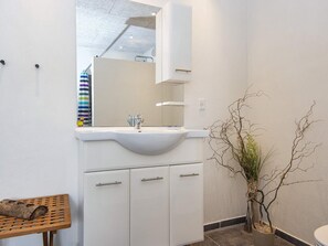 A bathroom with a white sink, mirror, and cabinets. There is a wooden bench and a potted plant. - 5 Star Holiday Home in Hemmet (Hemmet)