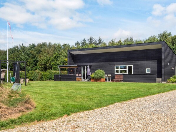 A modern two-story building with a flat roof, a covered patio area, and a well-maintained lawn.