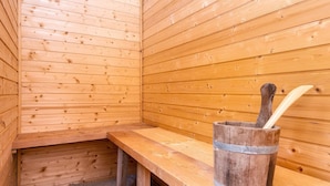 Una sauna de madera con bancos y un cubo de madera con una cuchara.