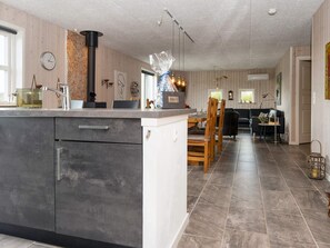 A modern kitchen with a central island, wooden dining table, and chairs. - 5 Star Holiday Home in Hemmet (Hemmet)