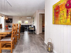 A dining area with a wooden table and chairs, a black sofa, and a TV mounted on the wall. - 5 Star Holiday Home in Hemmet (Hemmet)