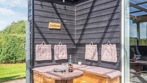 A wooden bench with a table in front, a sign reading 'JÖRG BRINK', and four towels hanging on the wall. - 5 Star Holiday Home in Hemmet (Hemmet)