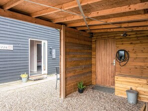 A wooden building with a gray exterior wall, a wooden door, and a small entrance.
