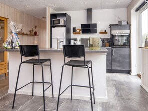 Eine moderne Küche mit Kochinsel, Barhocker, Mikrowelle, Herd und Kühlschrank.