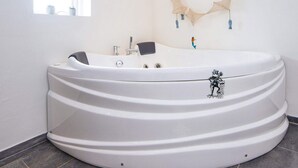 Un baño moderno con una bañera independiente grande, una ventana y un adorno de pared.