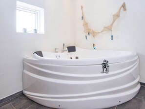 A modern bathroom with a large freestanding bathtub, a window, and a wall-mounted decorative piece. - 5 Star Holiday Home in Hemmet (Hemmet)