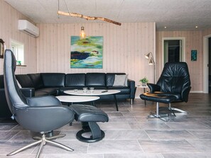 A modern living room with a black leather sofa, a round coffee table, and a black leather armchair. - 5 Star Holiday Home in Hemmet (Hemmet)