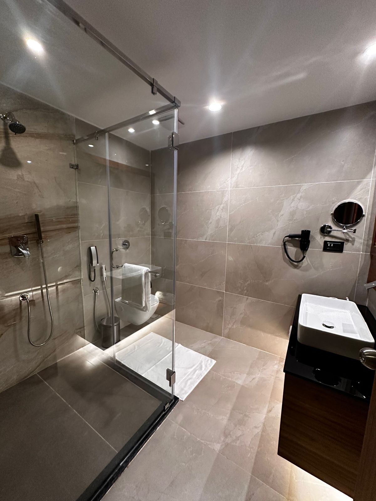 Ein modernes Badezimmer mit einer Duschkabine, einer Toilette und einem Waschbecken mit Spiegel.