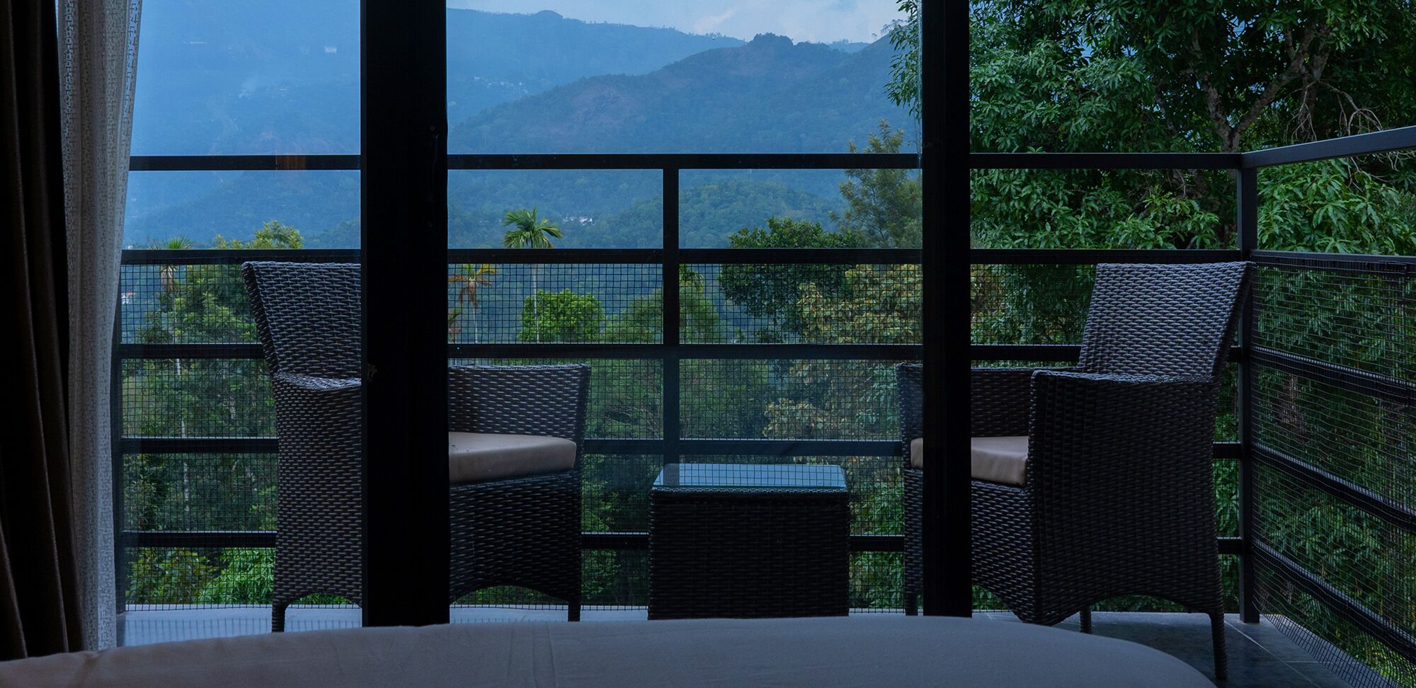 Un balcón con muebles de mimbre y vistas a las montañas.