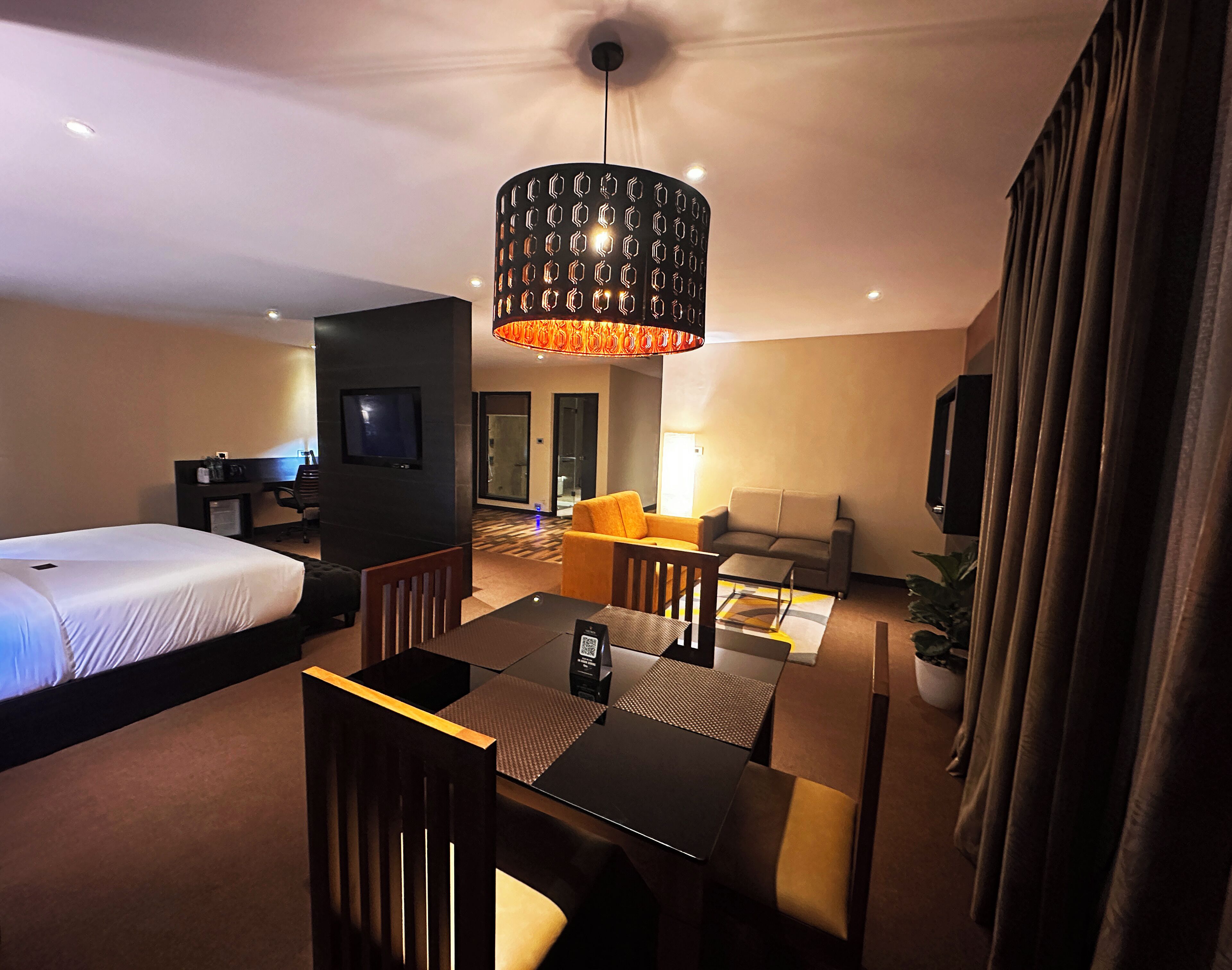 A hotel room with a bed, a desk, a sofa, and a dining table.