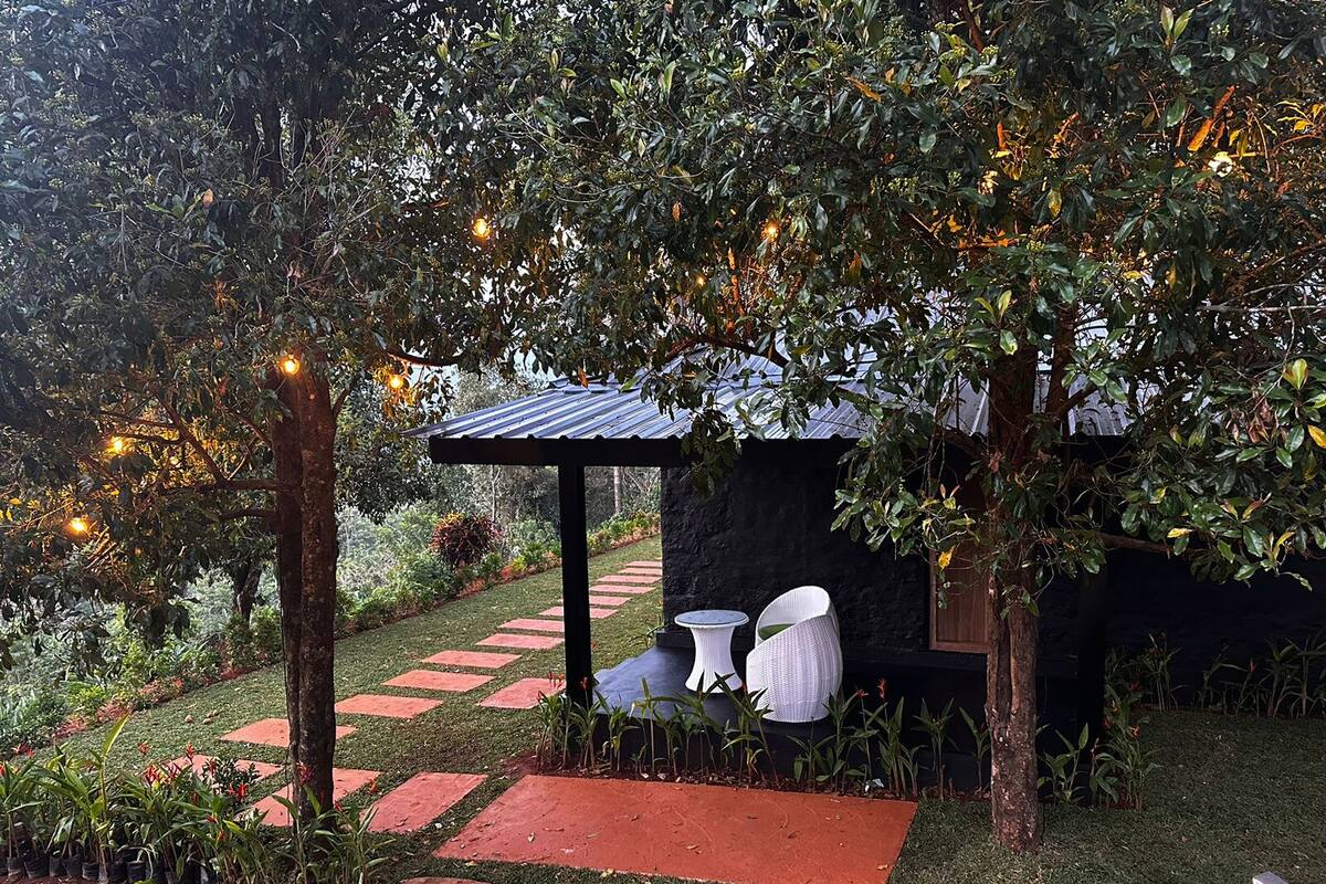 Un jardín con un pérgola, zona de estar y un sendero.