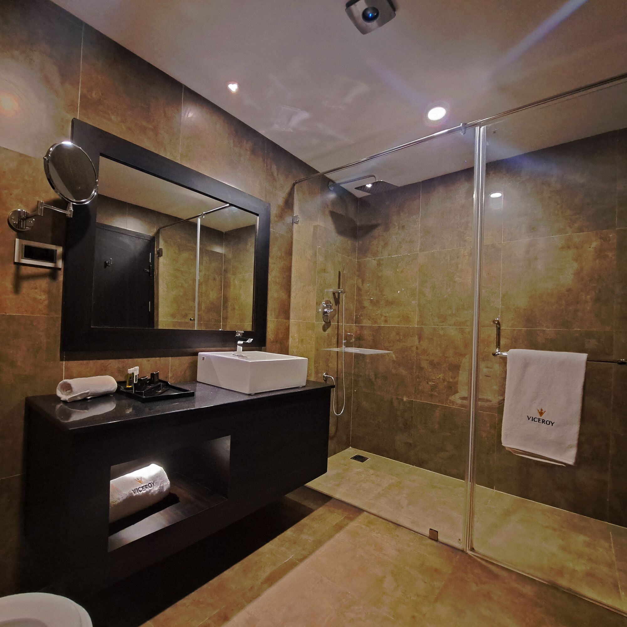 Un baño moderno con ducha de vidrio, un espejo grande y un lavamanos.