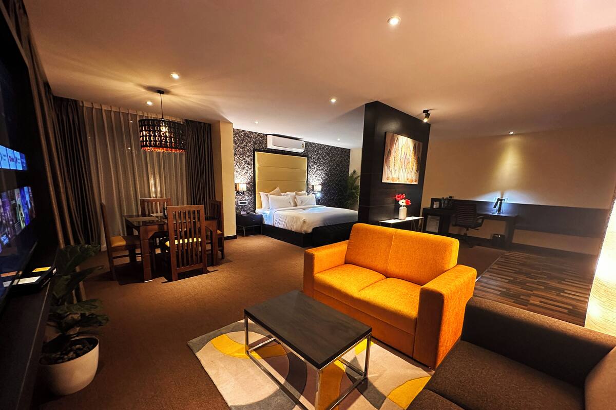 Una habitación de hotel con cama, sofá, televisor, escritorio y una silla.