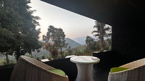 A balcony with wicker furniture and a view of a mountainous landscape. - Viceroy Luxury Mountain Resort (Udumbanchola)