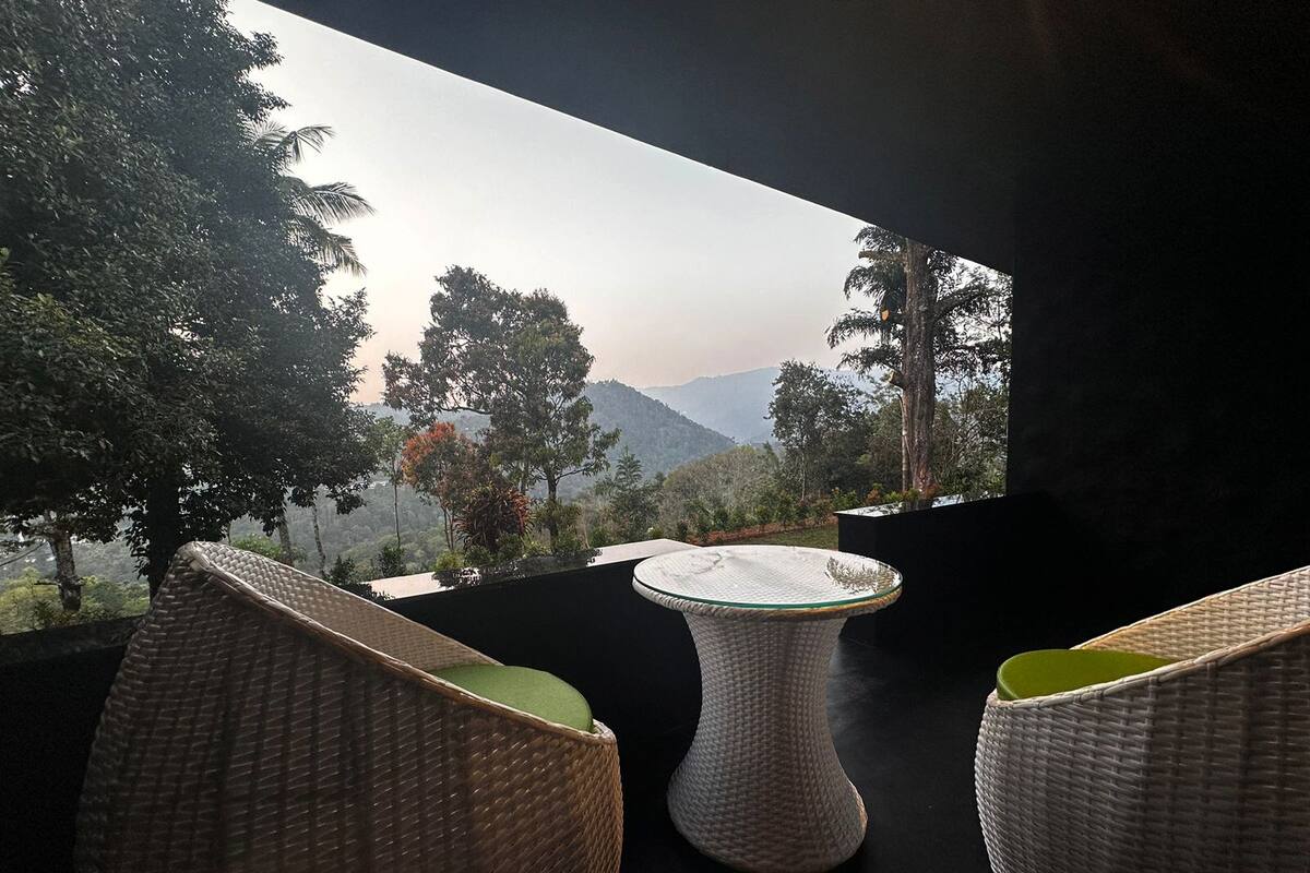 Un balcón con mobiliario de mimbre y vistas a un paisaje montañoso.