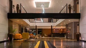 A modern lobby with a central staircase, seating area, and a reception desk. - Viceroy Luxury Mountain Resort (Udumbanchola)