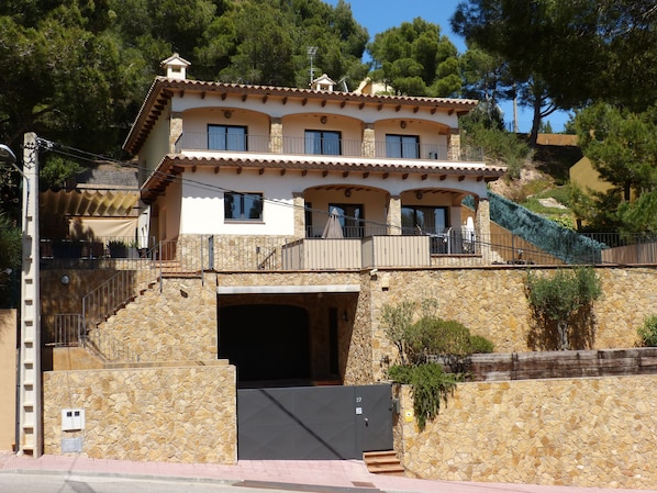A multi-story building with a stone facade, balconies, and a staircase leading to an entrance.