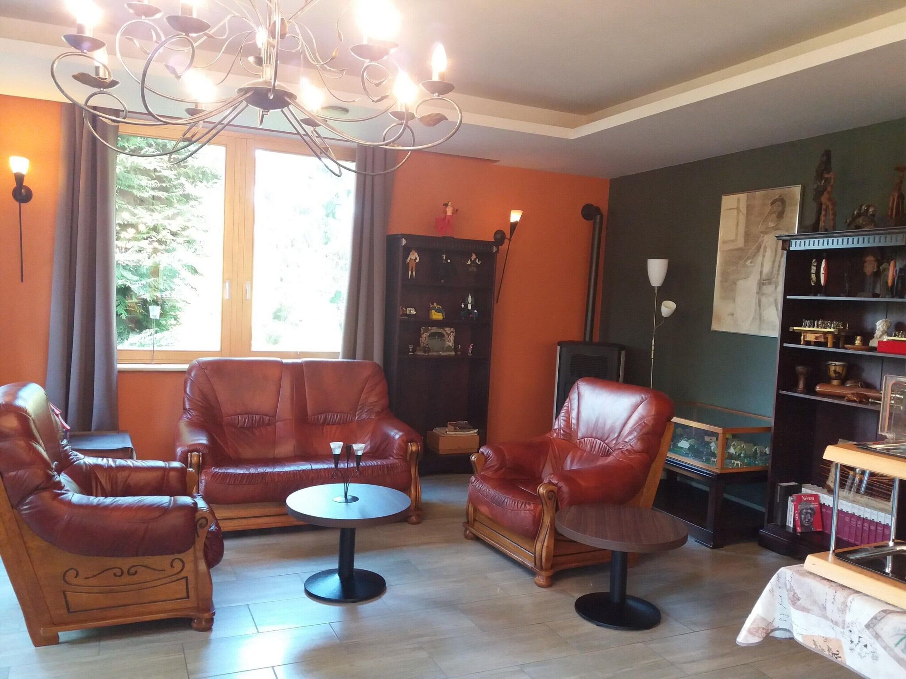 A living room with leather sofas, a round coffee table, and a bookshelf.
