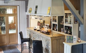 A bar area with stools, a counter, and shelves of bottles.