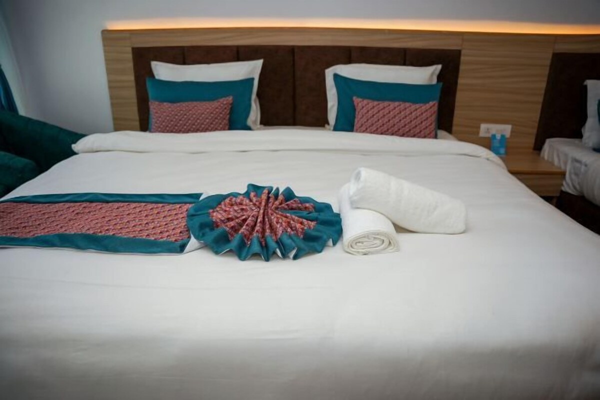 A neatly made bed with a decorative pillow arrangement and a rolled towel on a hotel room bed.