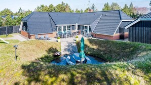 A modern building with a sloped roof, a patio area with outdoor seating, and a small water feature.