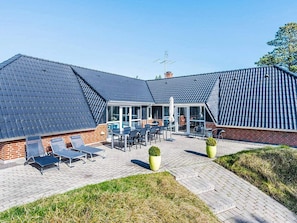 A building with a sloped roof, a patio area with outdoor furniture, and a brick facade. - 5 Star Holiday Home in Blavand (Blavand)