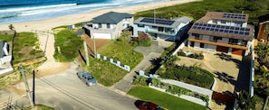 Una zona residenziale sulla costa, con case moderne, una spiaggia e un cielo sereno.