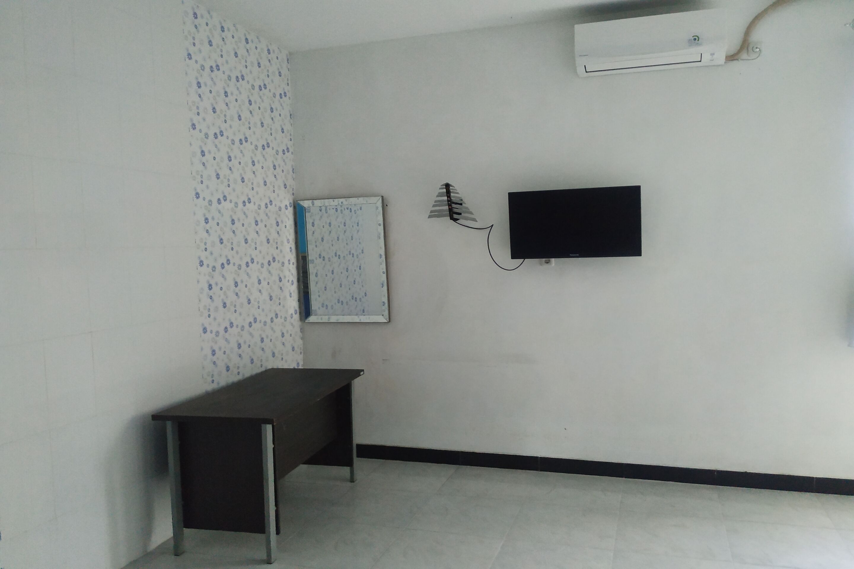 A room with a desk, a wall-mounted TV, and a whiteboard.