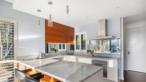 Una cocina moderna con una isla grande, armarios blancos y estufa integrada.