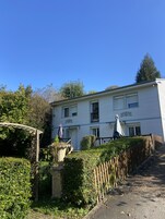 Un bâtiment à deux étages doté d’un jardin, d’une clôture en bois et d’une pergola.