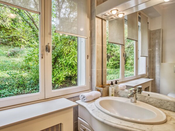 Un baño con un ventanal grande, un lavabo y un espejo.