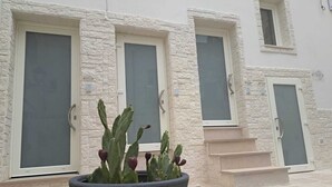 A building with three doors, each with a glass panel and a handle. There is a large planter with cacti in front of the doors. - 1 Bedroom Bed & breakfast in Grottaglie (Grottaglie)