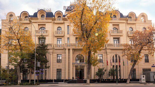 A large, historic building with a prominent entrance, multiple balconies, and flags. - Baden-Baden Hotel (Tashkent)