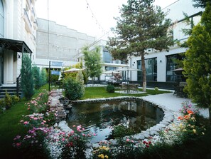 A courtyard with a pond, outdoor seating, and a building with large windows.