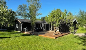 A cabin with a deck, a barbecue area, and a small shed.