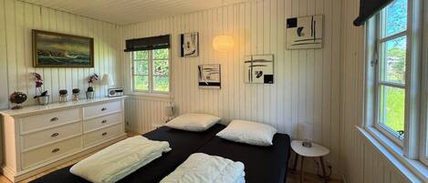 Un dormitorio con cama, cómoda, obra de arte y ventana con vistas.