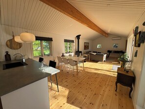 A spacious kitchen with a dining area, wooden floors, and a high ceiling with exposed beams. - Big Renovated Cottage With Soul and Love (Grevinge)