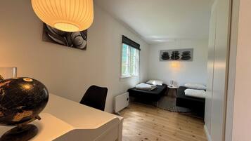 A compact room with a globe on a desk, a bed with a pillow, a small table, and a window with a view.