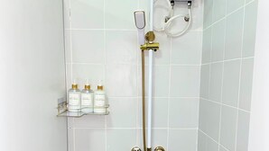 Une salle de bain équipée d’une douche, de toilettes et d’une étagère où sont rangés les articles de toilette.