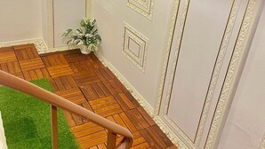 Une pièce dotée d’un parquet en bois à motifs en chevrons, de murs blancs agrémentés de moulures décoratives et d’une petite plante en pot.