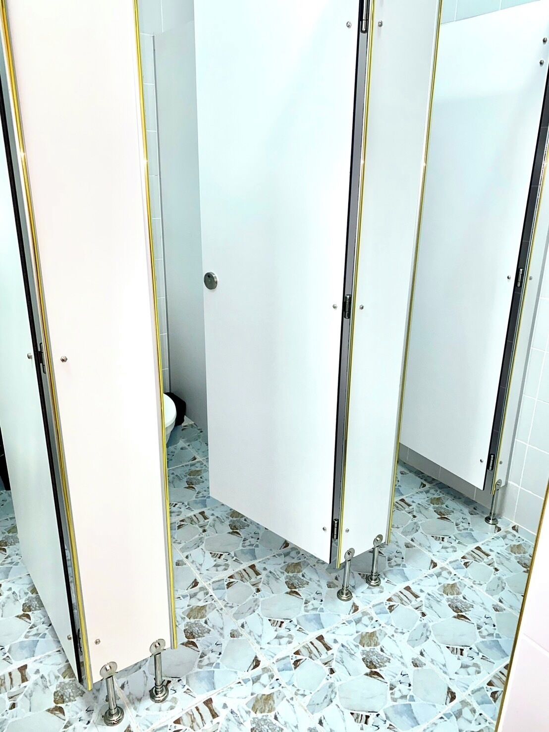 A restroom with white stalls and a tiled floor.