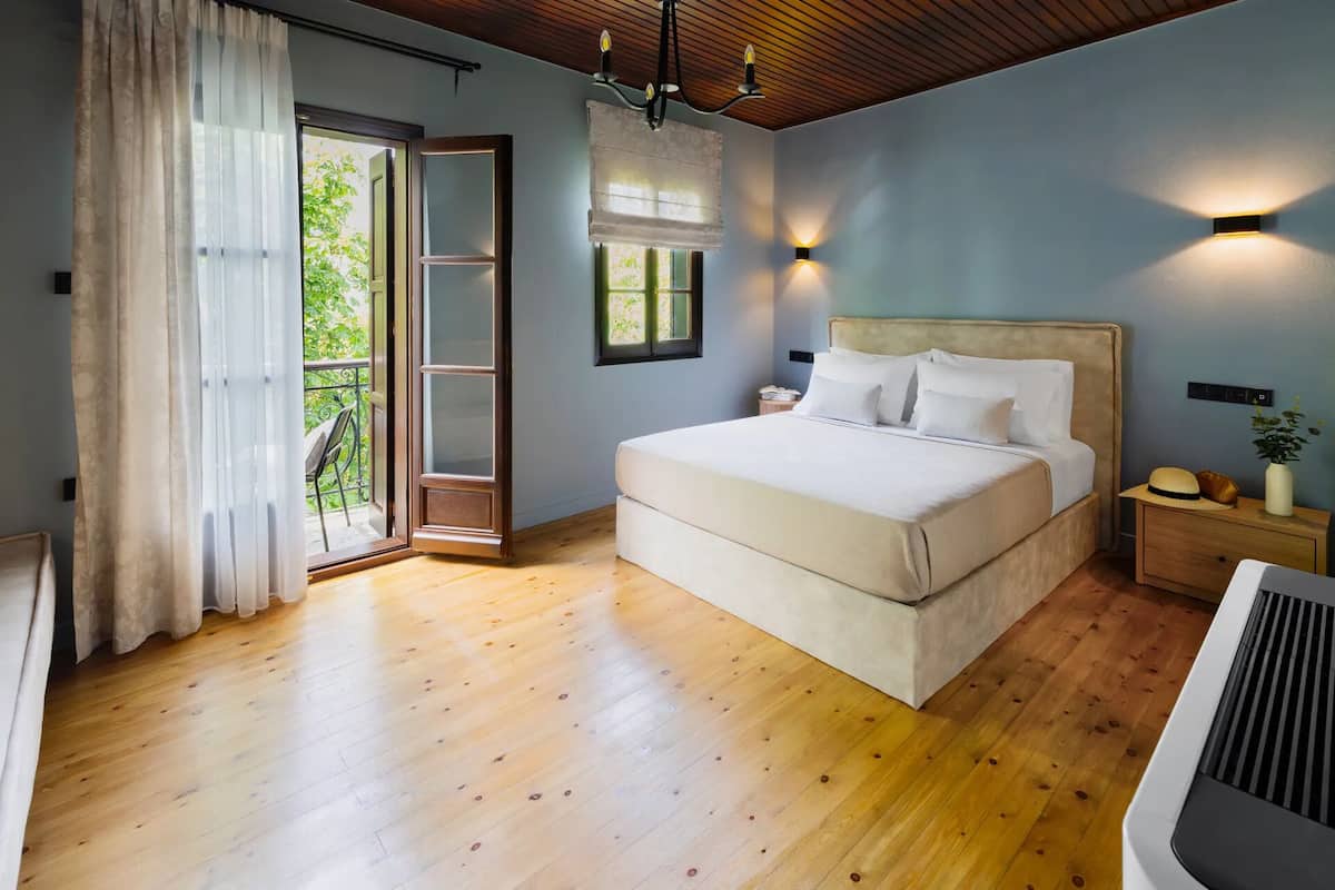 A bedroom with a bed, wooden flooring, a balcony door, and a ceiling fan.