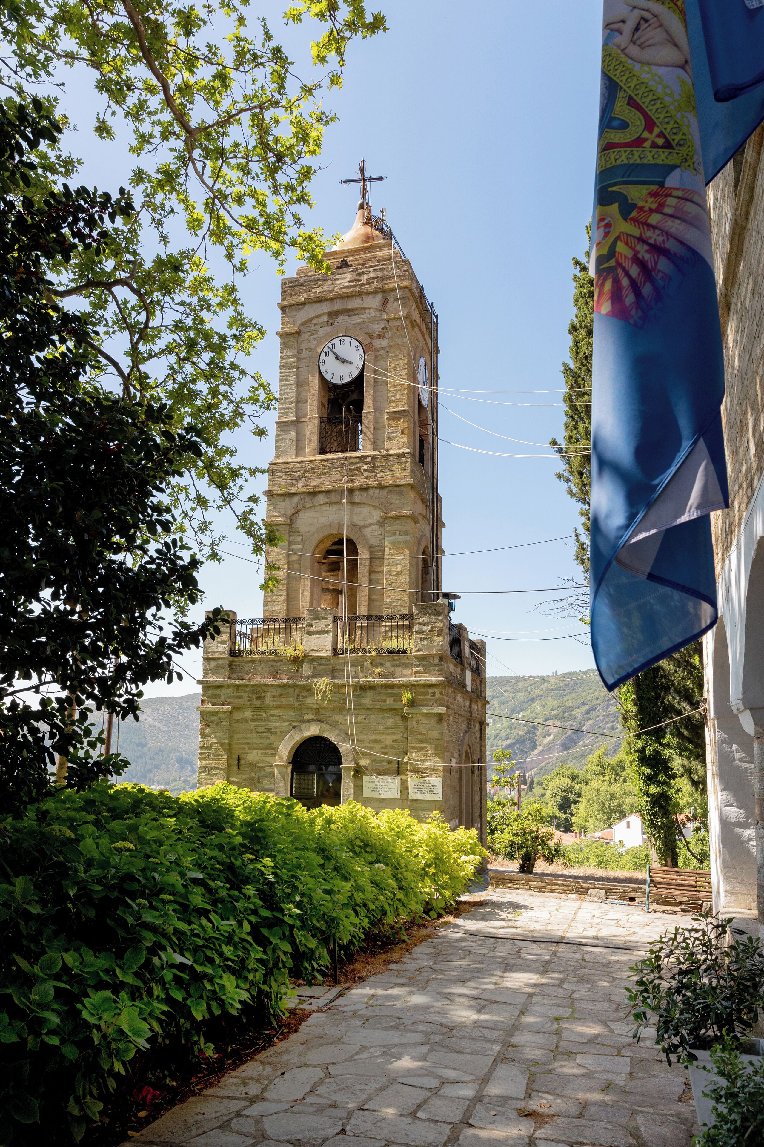 Una iglesia de piedra histórica con un campanario, un reloj y un camino que la lleva a ella.