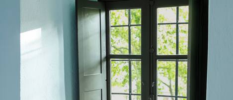 Una ventana con repisa de madera y un florero con flores.